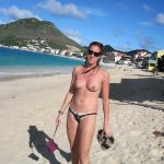 Une touriste bronzée s'exhibe topless sur une plage de sable fin